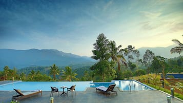 Una piscina al aire libre, sombrillas, sillones reclinables de piscina