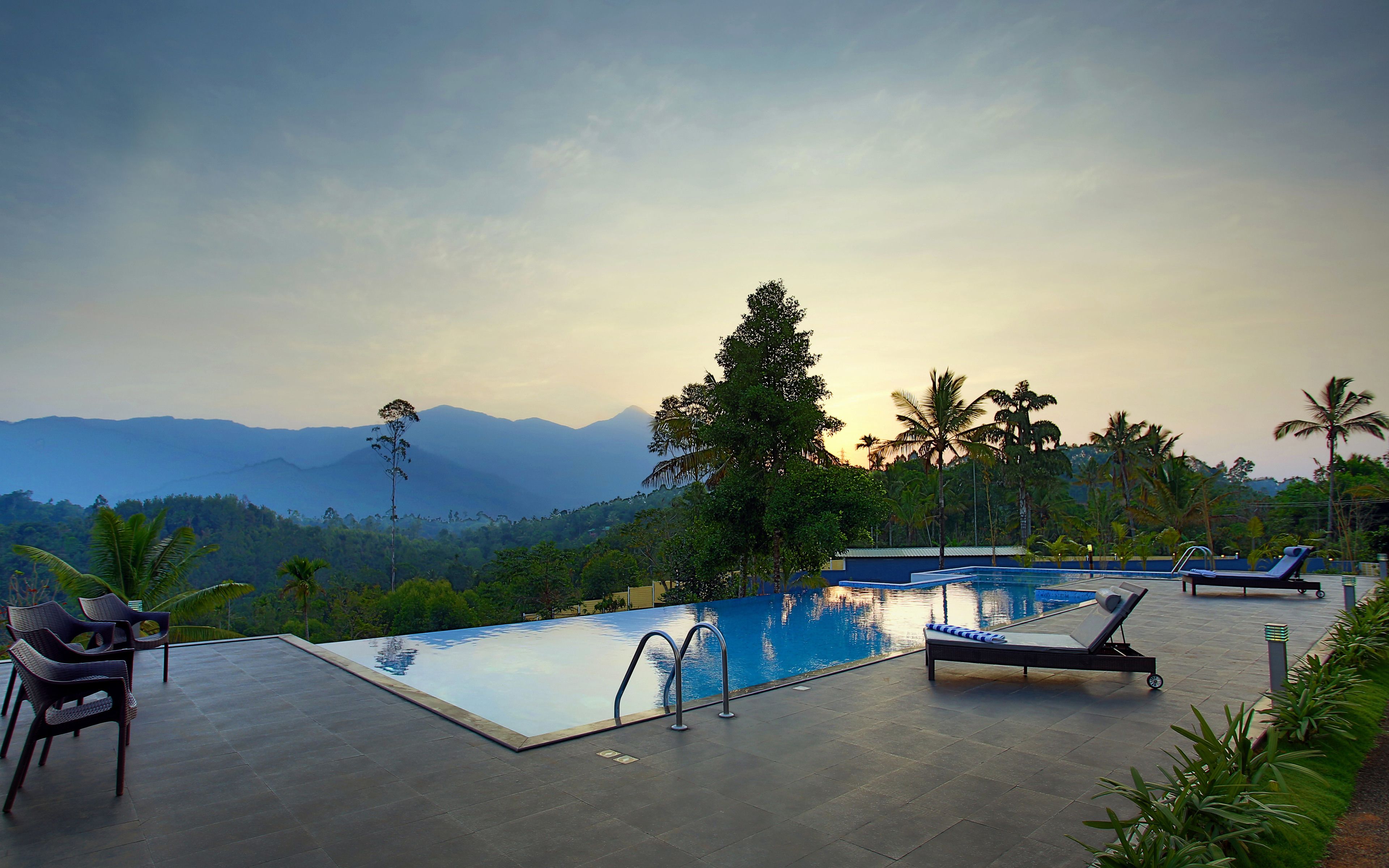Zona de piscina con sillones de descanso y vistas a las montañas.