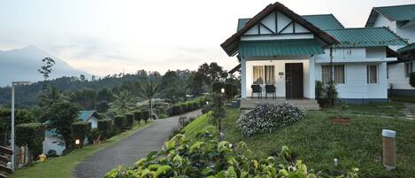 A modern hotel with a green roof, a paved driveway, and lush landscaping.