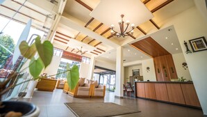 A spacious hotel lobby with a high ceiling, wooden beams, a large chandelier, and a reception desk. - The Leaf Munnar Resort (Devikolam)