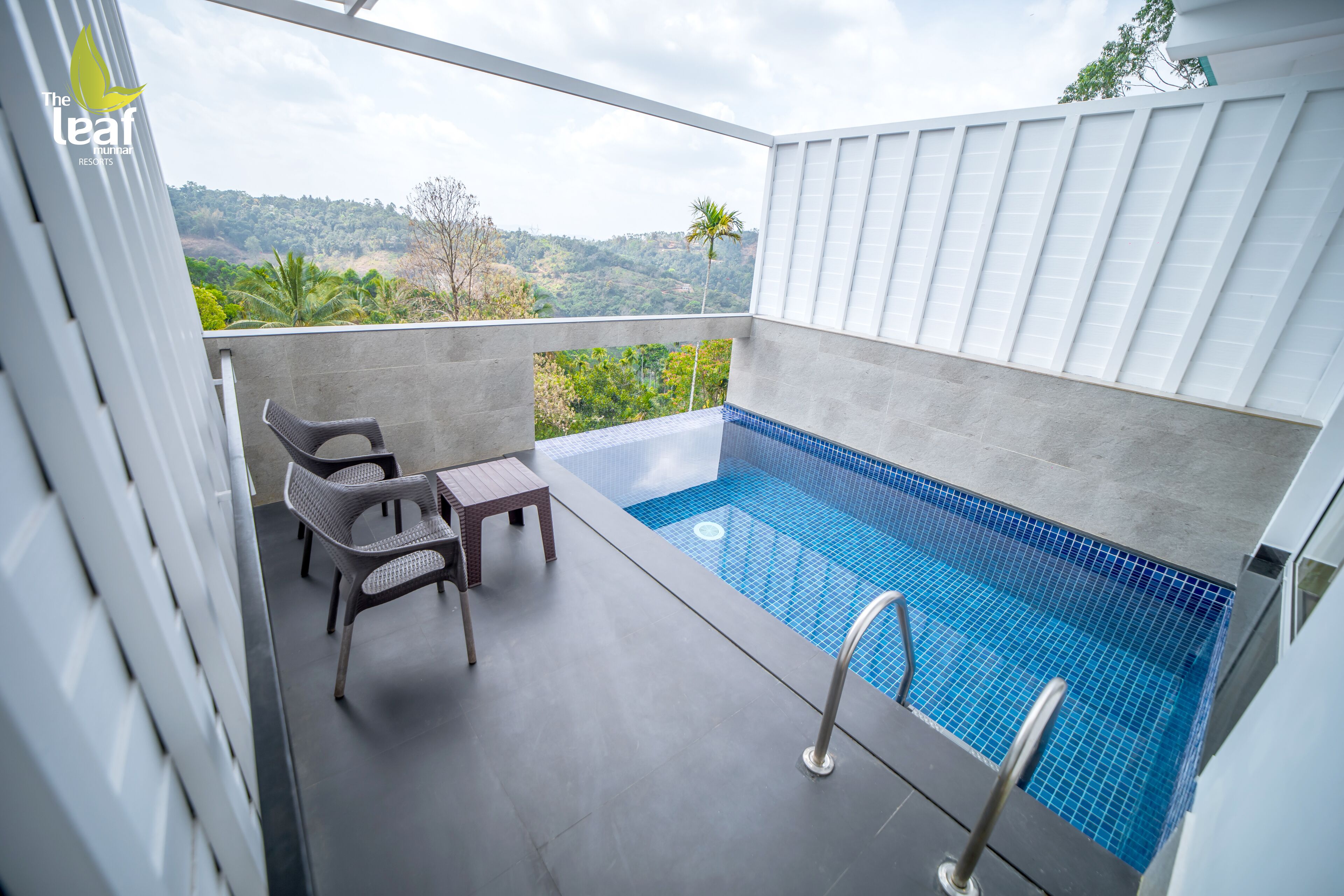A balcony with a small pool, wicker chairs, and a table.