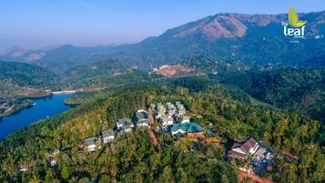 Un resort con varias edificaciones rodeado de un bosque denso y colinas.