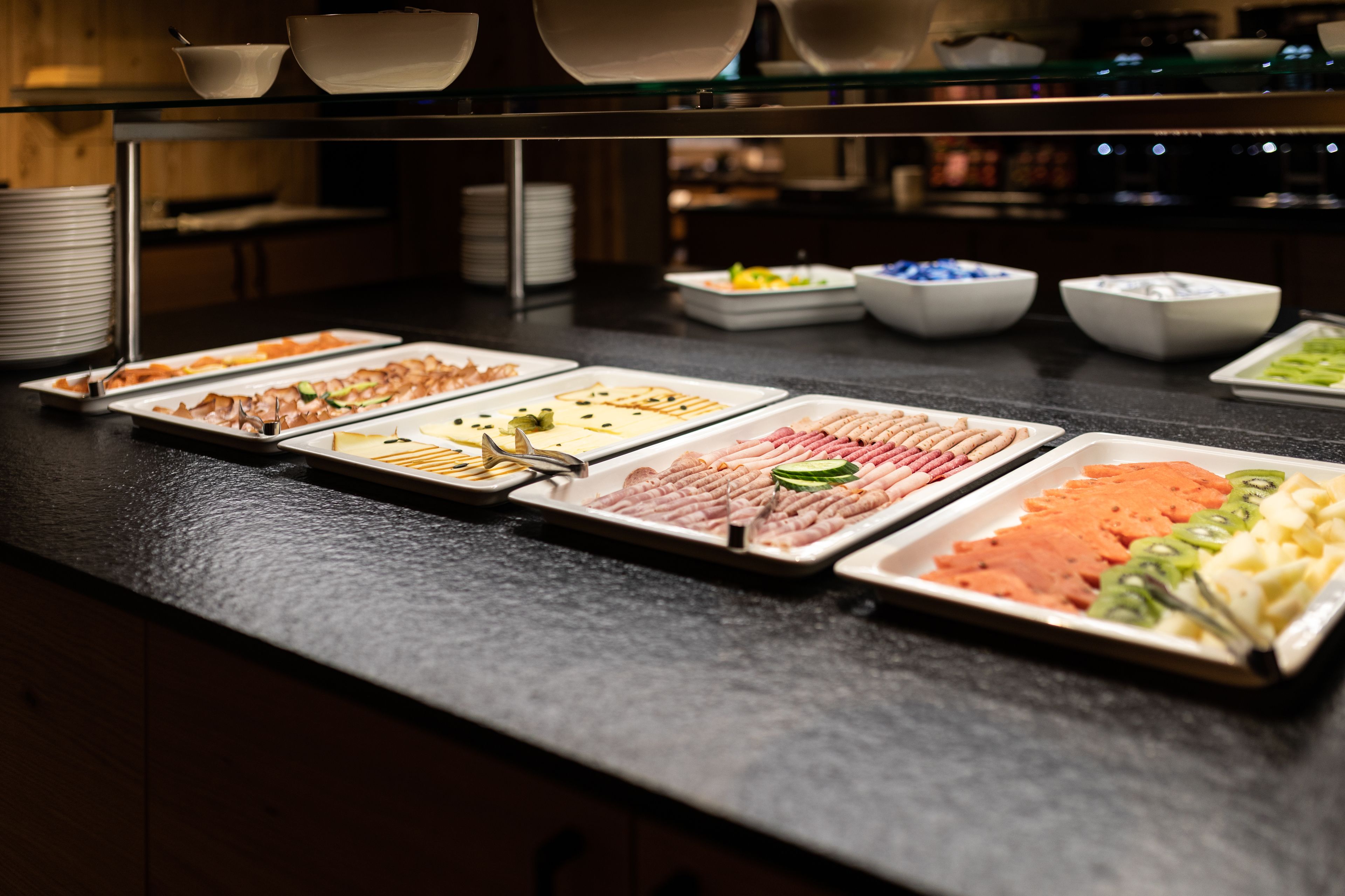 Un buffet proposant une variété de plats, notamment des viandes, des légumes et des fruits.