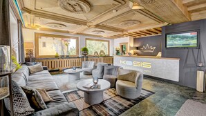 A modern hotel lobby with a reception desk, comfortable seating, and a large window providing natural light. - KOSIS Sports Lifestyle Hotel (Fuegen)