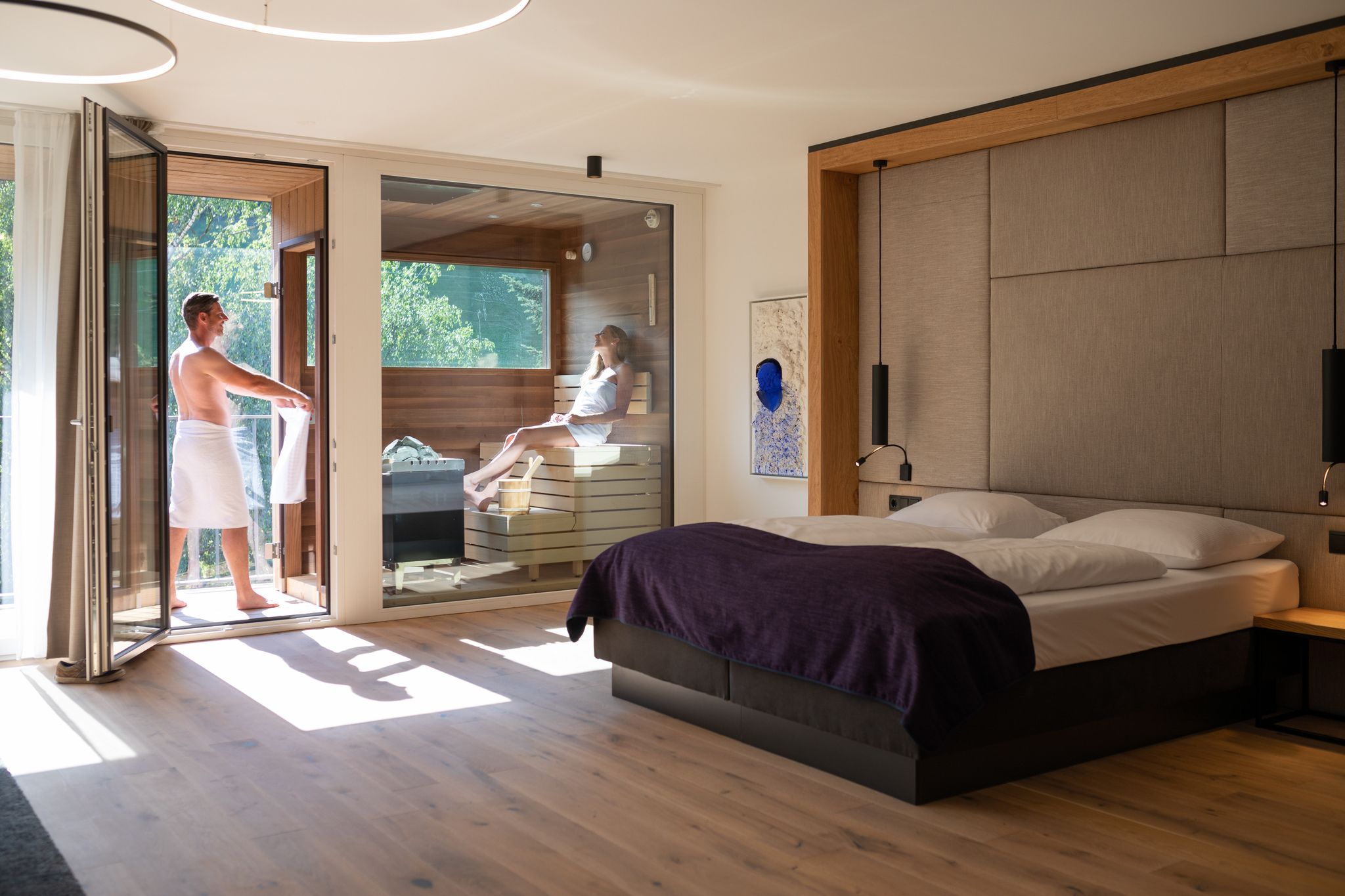 Une chambre moderne avec un grand lit, un plancher en bois et une porte-fenêtre coulissante donnant sur un espace extérieur.