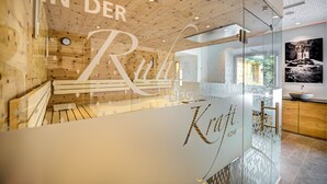 A modern interior with a wooden ceiling, a glass wall with a name inscription, and a wooden bench. - KOSIS Sports Lifestyle Hotel (Fuegen)