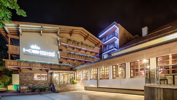 A hotel with a prominent sign reading "KOSIS SPORTS LIFESTYLE HOTEL" and a "WINE & DINE" section. - KOSIS Sports Lifestyle Hotel (Fuegen)