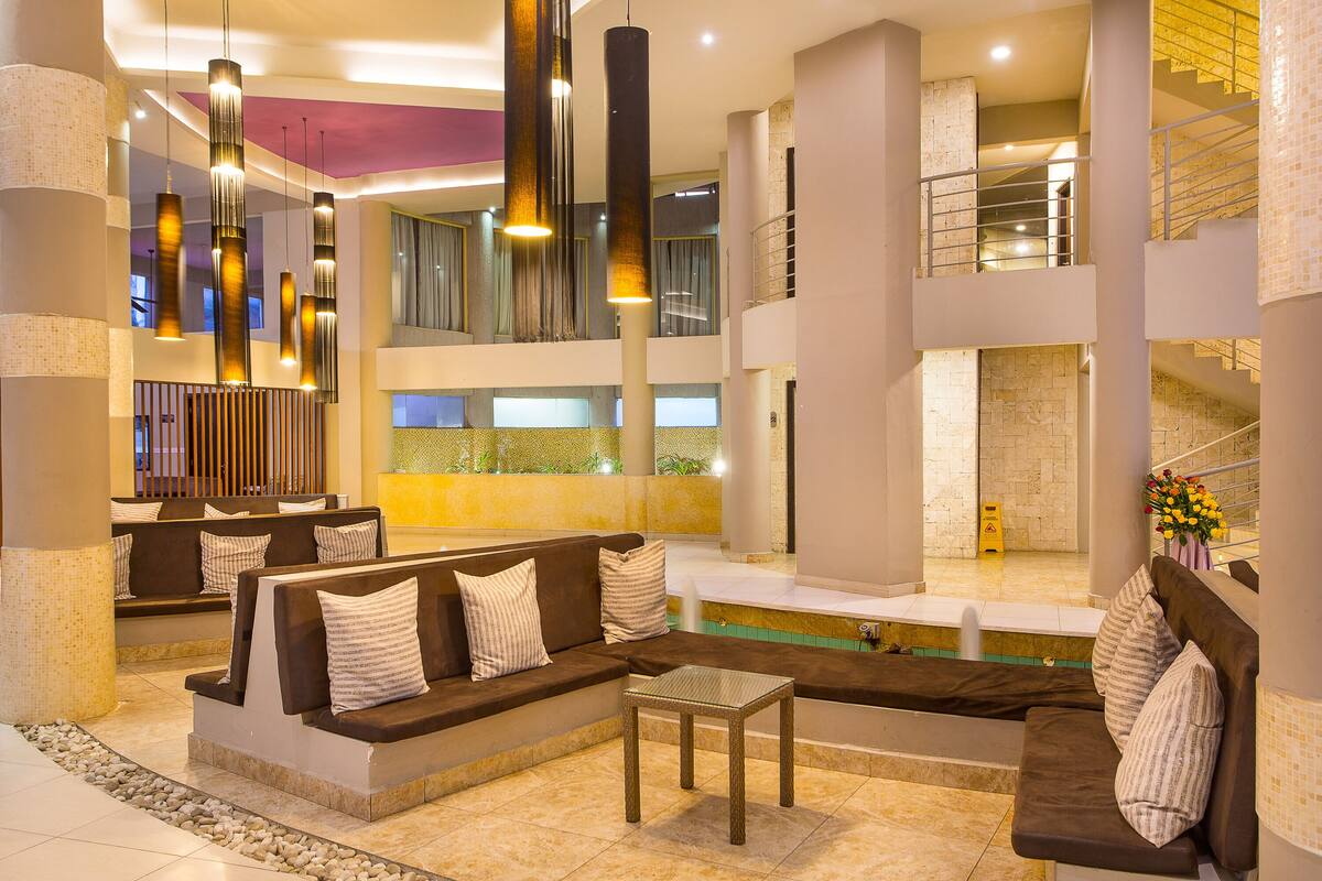 Um lobby moderno com piscina, áreas de estar e uma escadaria.