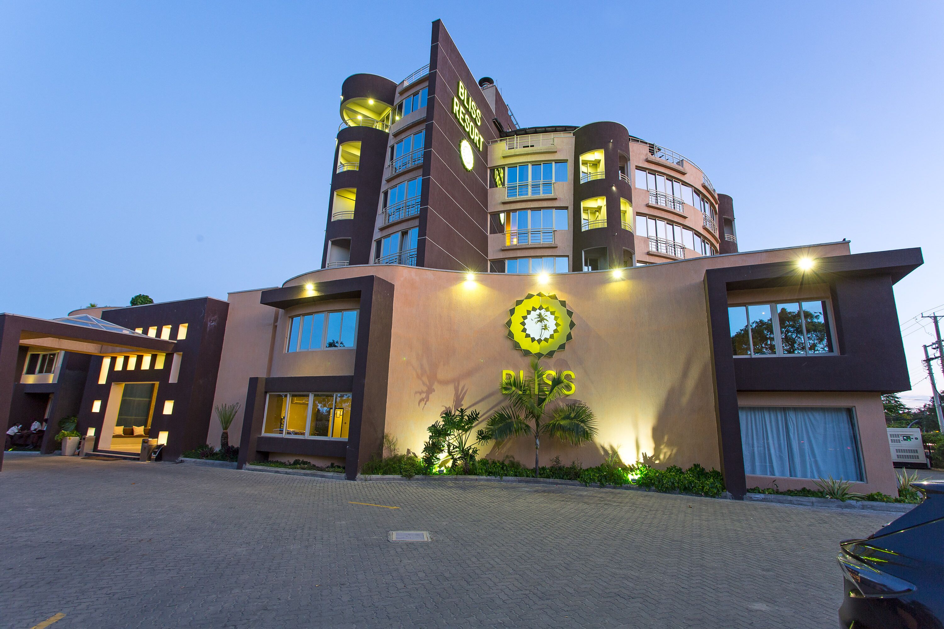 Un hotel moderno con un reloj destacado, varios balcones y una entrada bien iluminada.