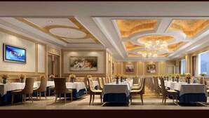 Une salle à manger élégante, avec des tables dressées pour le service, un lustre et des œuvres d’art accrochées aux murs.