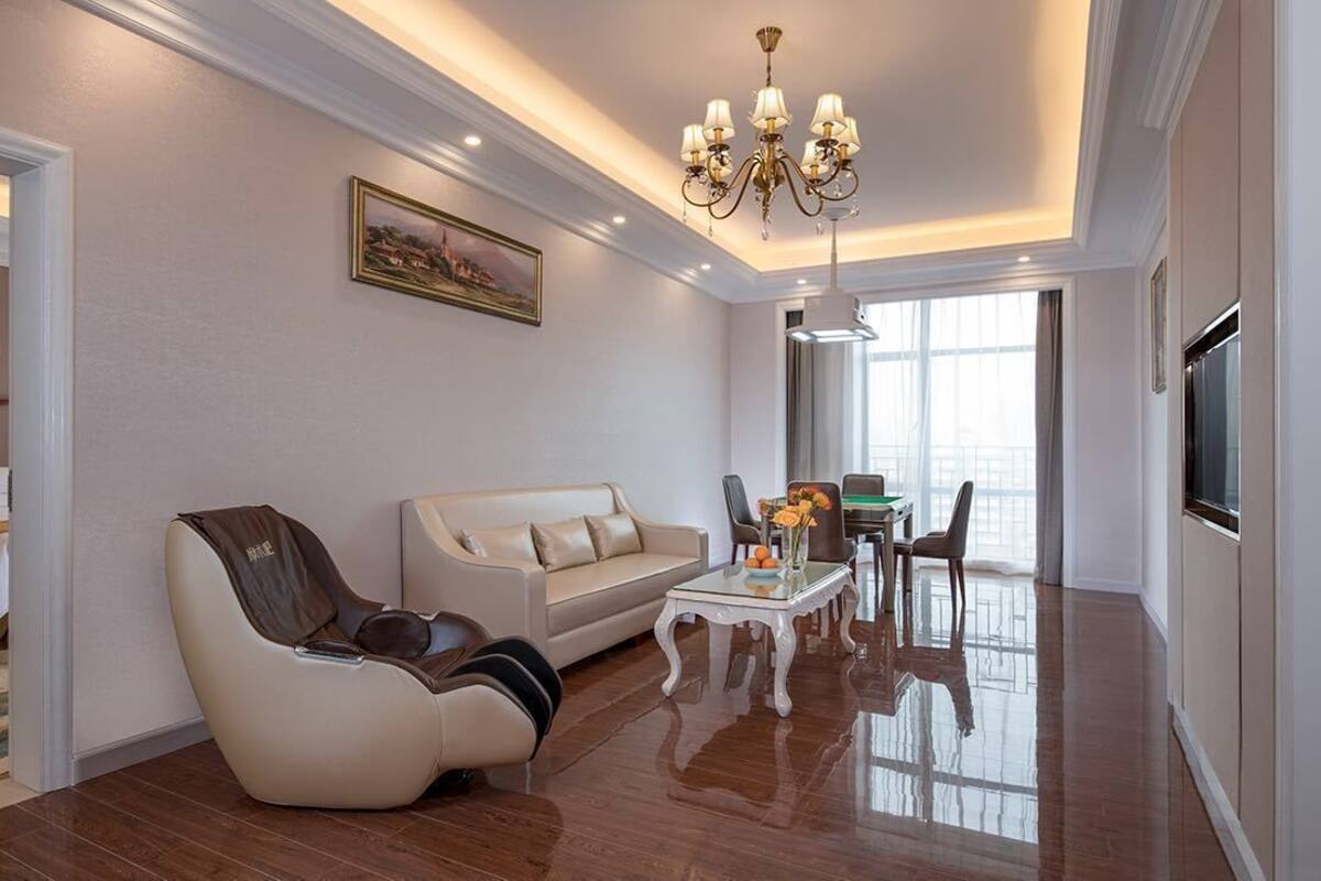 Een moderne hotelkamer met een bank, fauteuil en een zithoek met een tafel en stoelen.