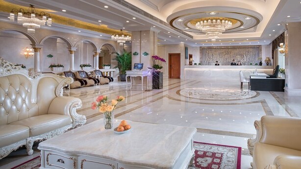 Un hall d’entrée luxueux, agrémenté de canapés richement décorés, d’un comptoir de réception et d’un sol en marbre.