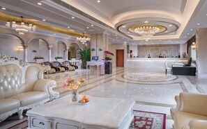 A luxurious lobby with ornate sofas, a reception desk, and a marble floor.