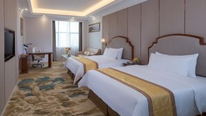 Une chambre d’hôtel avec deux lits, un bureau, une chaise, une télévision et une grande fenêtre.