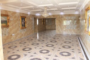 A spacious lobby with a patterned floor, marble walls, and a chandelier. - Grand Emperor Hotel (Lekki)