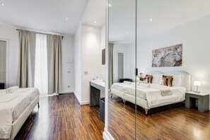A modern hotel room with a large bed, a desk, a chair, a bedside table, and a mirror. - Xenia Guest House (Rome)