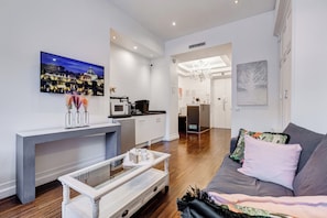 A modern living room with a sofa, coffee table, and a painting of a cityscape. - Xenia Guest House (Rome)