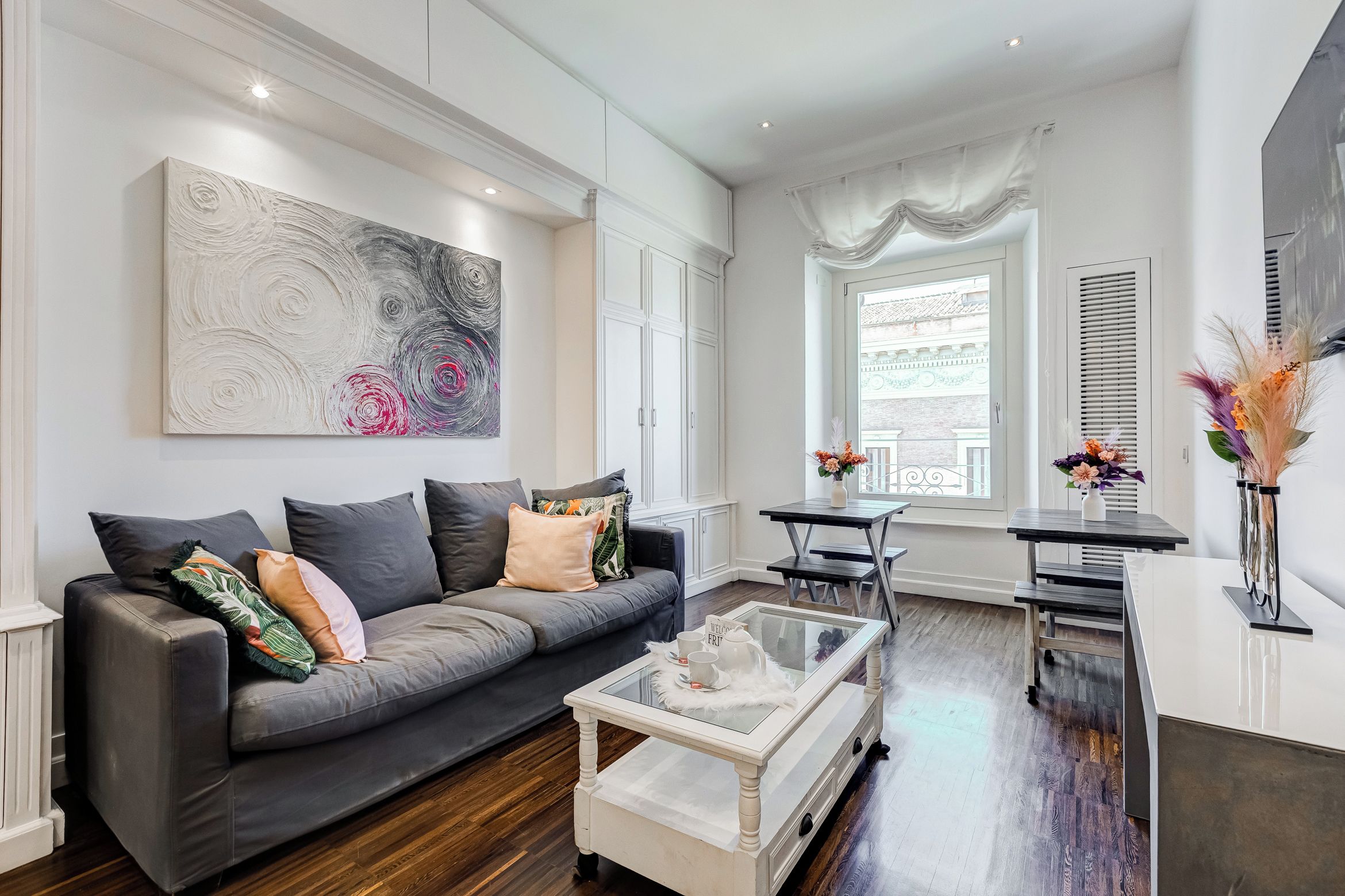 A modern living room with a grey sofa, a coffee table, and a large abstract painting on the wall.