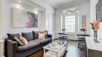 A modern living room with a grey sofa, a coffee table, and a large abstract painting on the wall.