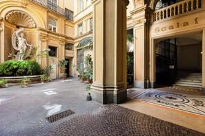 A hotel entrance with a classical statue, potted plants, and a tiled floor. - Xenia Guest House (Rome)