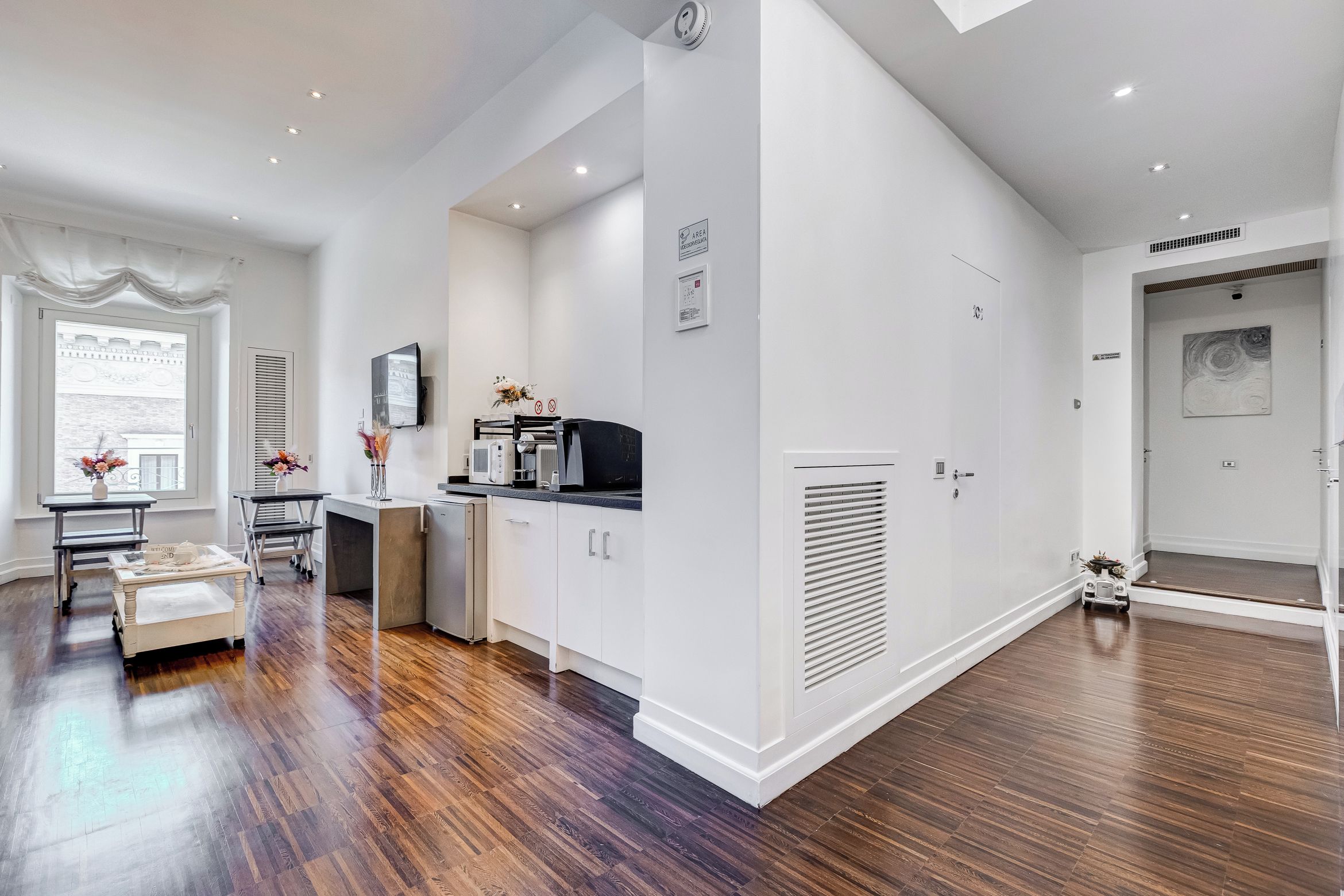 A modern kitchen with white cabinets, a built-in microwave, and a coffee machine.