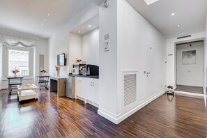 A modern kitchen with white cabinets, a built-in microwave, and a coffee machine. - Xenia Guest House (Rome)