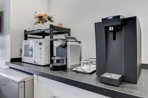 A commercial kitchen with a coffee machine, a microwave, and a refrigerator. - Xenia Guest House (Rome)