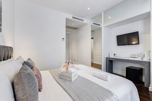 A modern hotel room with a bed, a seating area, a flat-screen TV, a coffee machine, and a mirror. - Xenia Guest House (Rome)