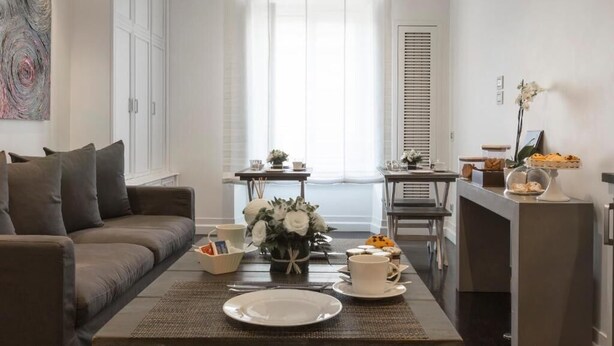 Una sala de estar moderna con un sofá, una mesa de comedor y una mesa de centro con un plato y tazas.