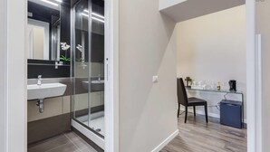 A modern bathroom with a glass shower enclosure, a sink, and a mirror. - Hanky Suite (Rome)