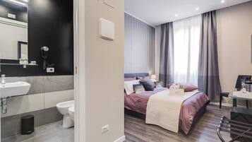 Une chambre d’hôtel moderne comprenant une salle de bain, un lit avec une tête de lit, un bureau et une chaise.