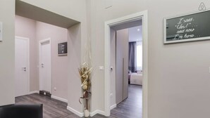 A hallway with a modern interior, a black leather chair, and a decorative vase. - Hanky Suite (Rome)