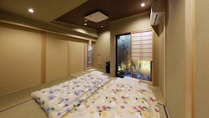 A traditional Japanese-style room with tatami flooring, a shoji screen door, and a bed with floral bedding.