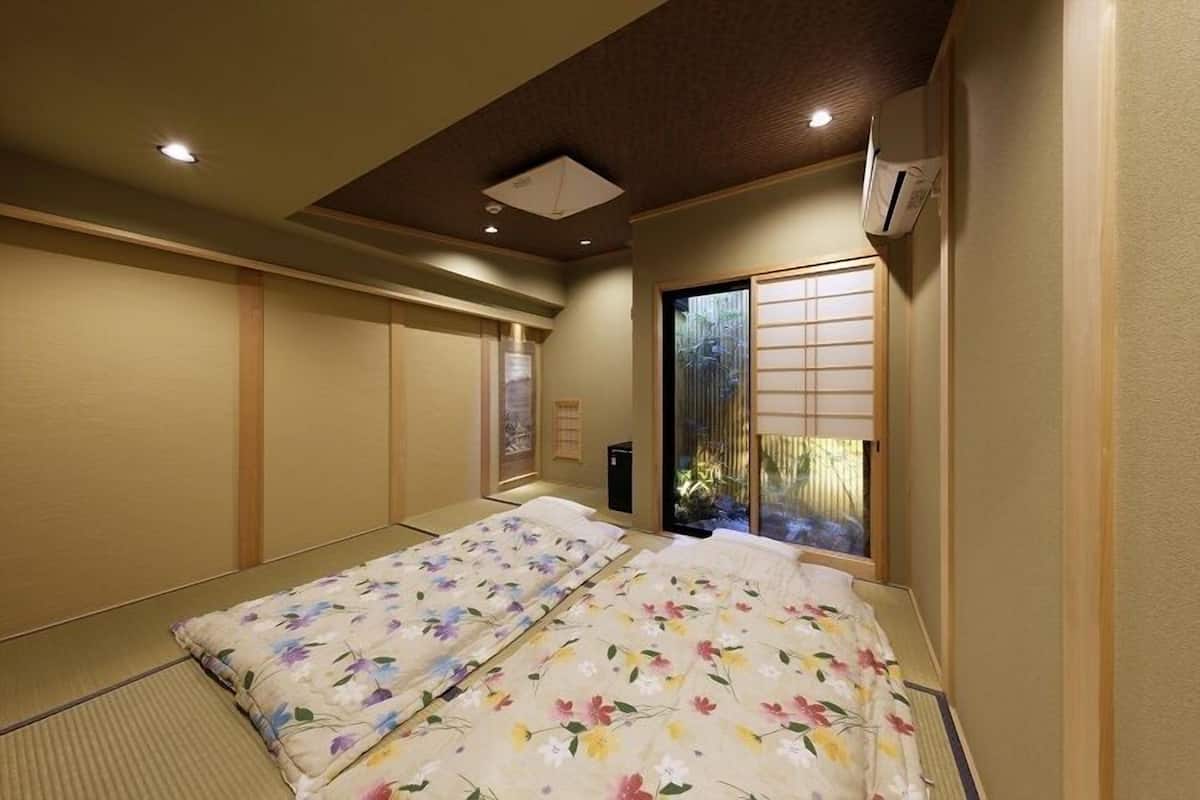 A traditional Japanese-style room with tatami flooring, a shoji screen door, and a bed with floral bedding.
