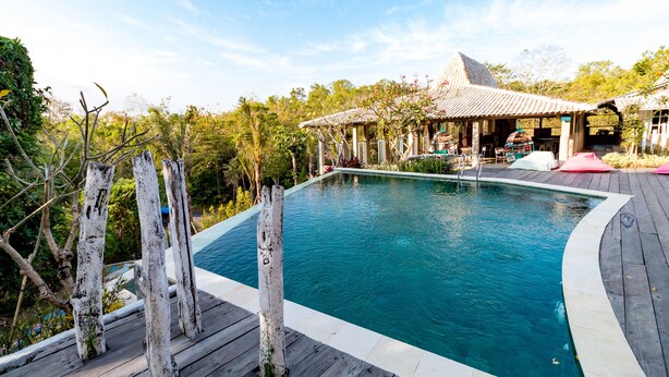 Piscina com deck de madeira e um gazebo ao fundo.