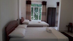 A hotel room with two single beds, a wardrobe, and a window with curtains. - Risenlak Holiday Resort (Polonnaruwa)