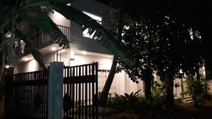 A modern two-story building with a gated entrance, surrounded by tropical vegetation. - Risenlak Holiday Resort (Polonnaruwa)