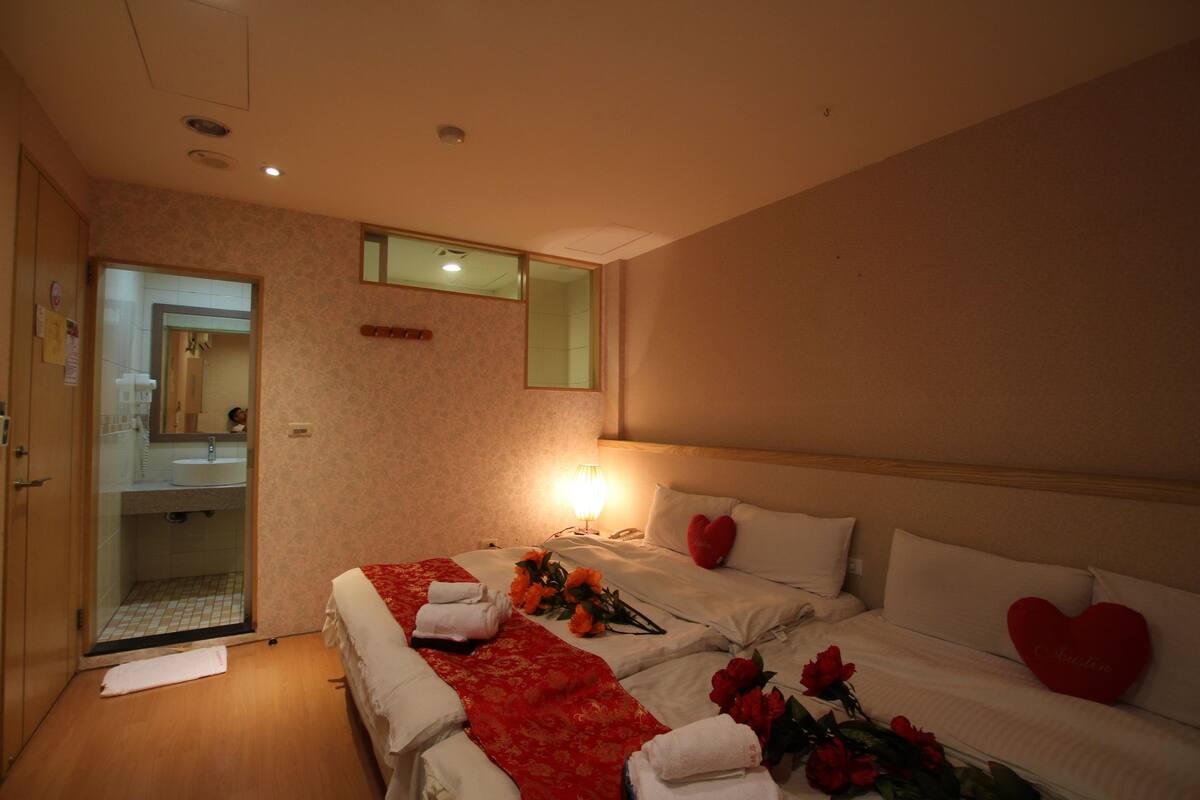 A hotel room with two beds, a bathroom, and a mirror.