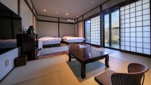 Et traditionelt japansk rum med tatamimåtter, to senge, et træbord og udsigt gennem shoji-skærme.
