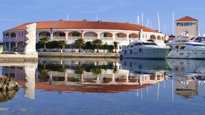 A waterfront property with a large building featuring arched balconies and a red-tiled roof.