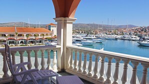 A balcony with white balustrades, a white chair, and a small table.