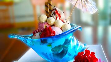 A dessert in a blue glass bowl with various toppings, including a small umbrella.