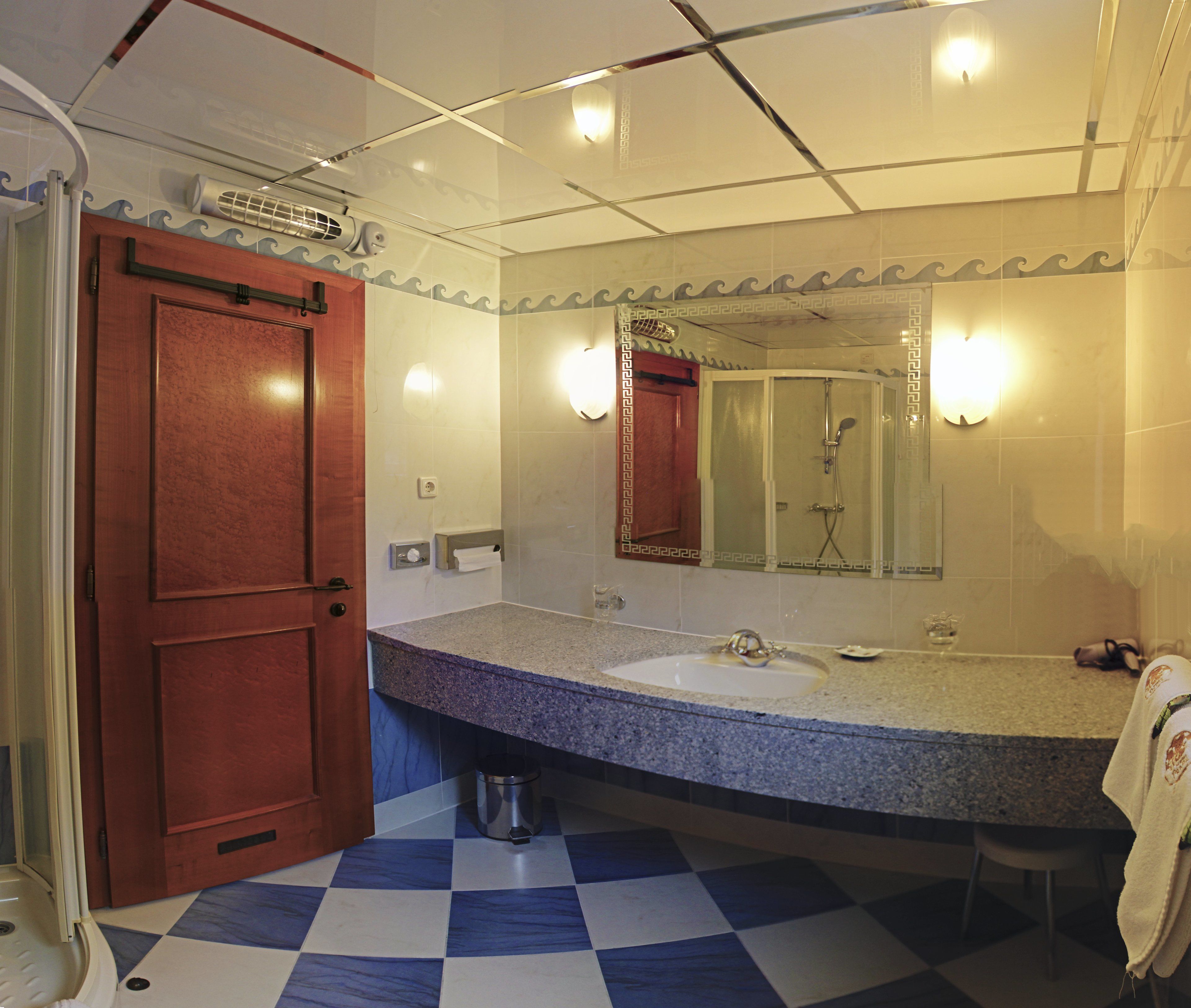 A bathroom with a checkered floor, a sink, a mirror, and a shower.