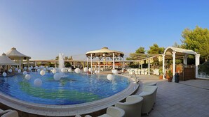 A pool area with a central fountain, surrounding lounge chairs, and covered seating areas.