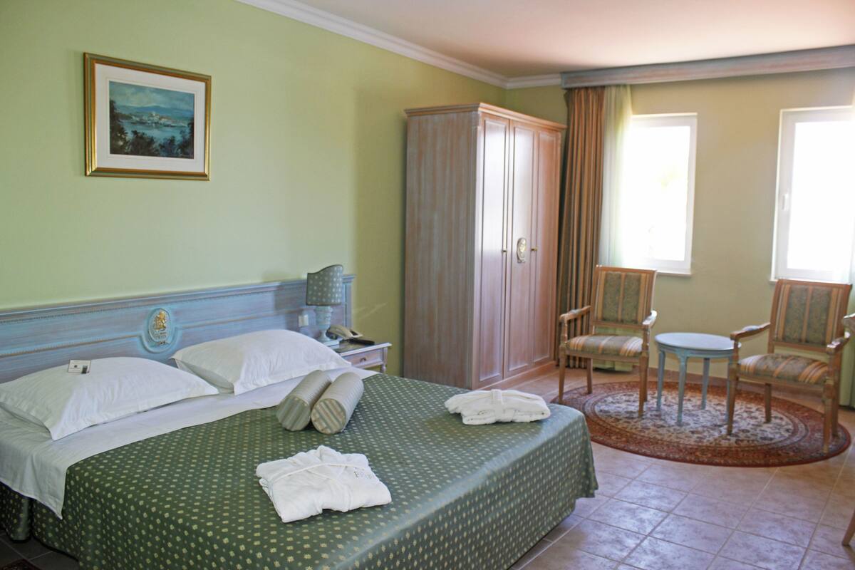 Ein Hotelzimmer mit Bett, Schrank, Stuhl und kleinem Tisch.