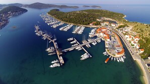 An aerial view of a marina with numerous boats docked, connected piers, and surrounding residential buildings.