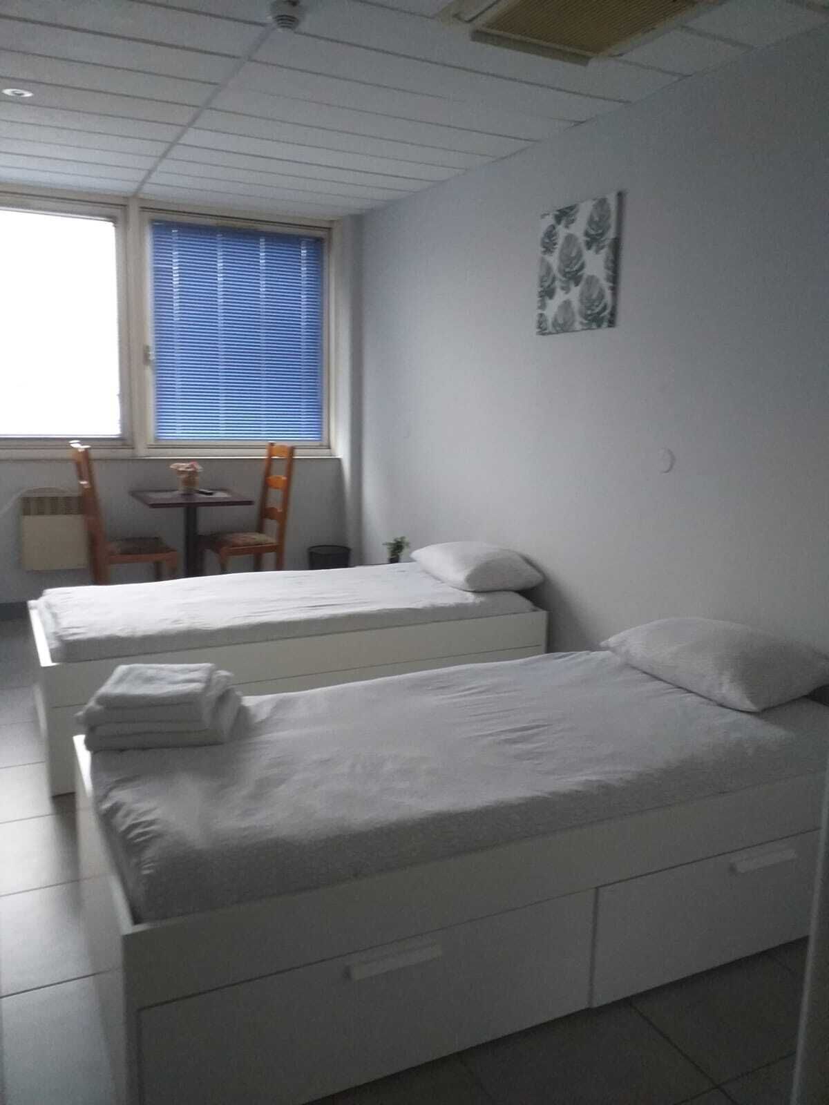 Een kamer met twee bedden, een tafeltje en een stoel.