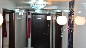 Un couloir avec une porte sombre, des luminaires décoratifs et un élément décoratif en vitrail.
