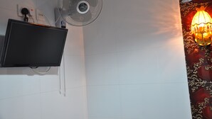 Une pièce dotée d’un téléviseur fixé au mur, d’un ventilateur de plafond et d’un appliques murales décoratives.