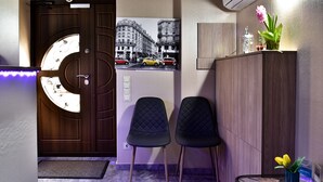 A hotel lobby with a wooden door, two black chairs, a glass table with a vase, and a wall-mounted air conditioner. - EXPO Hotel Comfort (Kyiv)